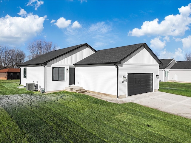 view of front of property with central AC unit, a garage, and a front lawn