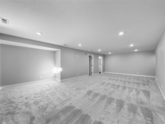 basement featuring a textured ceiling and light colored carpet