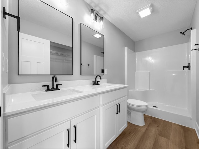 bathroom featuring walk in shower, vanity, a textured ceiling, wood-type flooring, and toilet