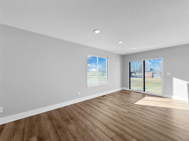 unfurnished room with hardwood / wood-style floors and a textured ceiling