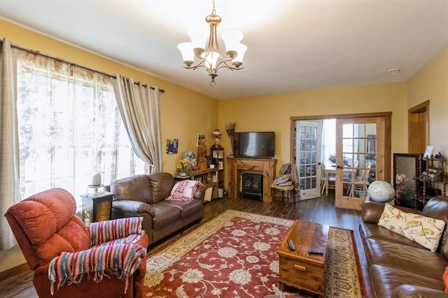 living area featuring french doors, a notable chandelier, wood finished floors, and a fireplace