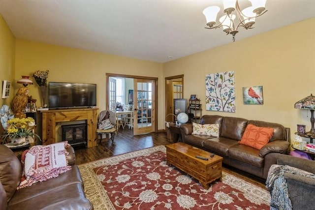 living room with a glass covered fireplace, a notable chandelier, and wood finished floors