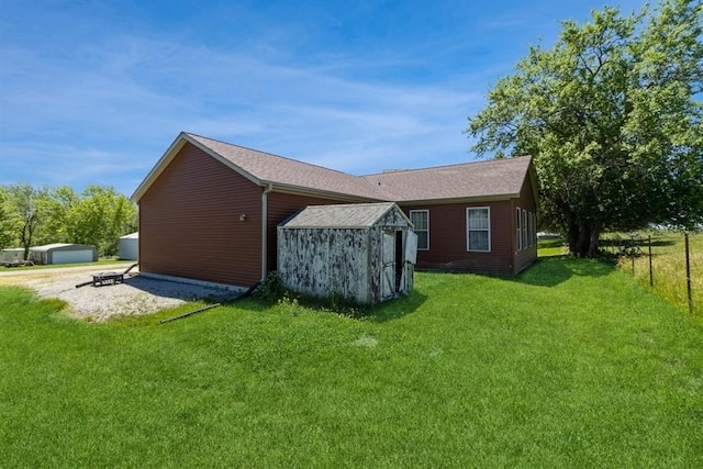 rear view of property with a lawn, an outdoor structure, and driveway