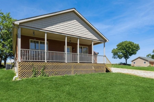 view of front of home featuring a front lawn, central AC, covered porch, and driveway