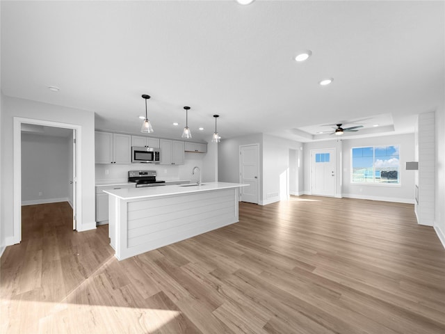 kitchen featuring a kitchen island with sink, light hardwood / wood-style flooring, hanging light fixtures, and appliances with stainless steel finishes