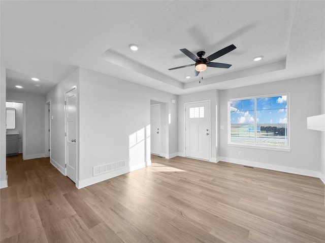 foyer featuring a tray ceiling, light hardwood / wood-style flooring, and ceiling fan