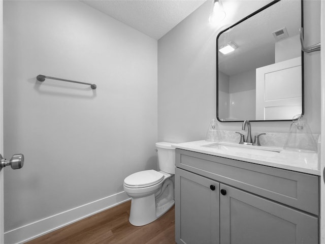 bathroom with vanity, wood-type flooring, a textured ceiling, and toilet