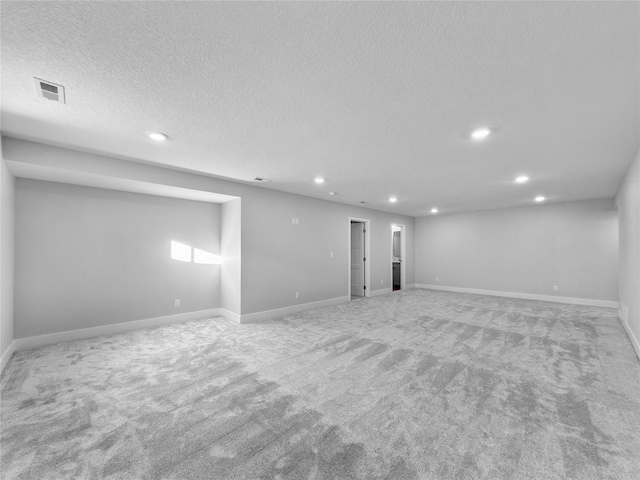 basement featuring light colored carpet and a textured ceiling