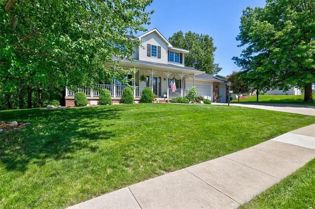 farmhouse inspired home with covered porch, a garage, and a front lawn