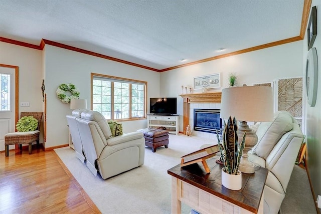 living room with hardwood / wood-style flooring, ornamental molding, a textured ceiling, and a tile fireplace