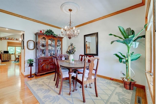 dining room featuring crown molding, a chandelier, and light wood-type flooring