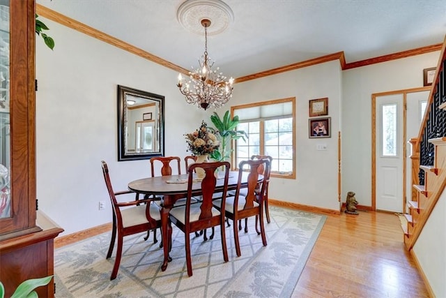 dining space featuring an inviting chandelier, ornamental molding, and light hardwood / wood-style flooring