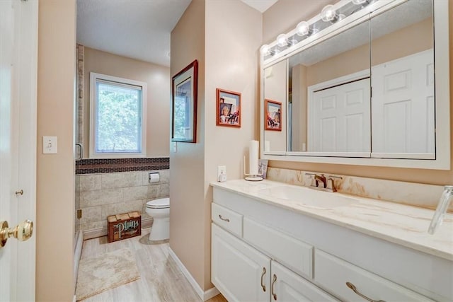 bathroom featuring tile walls, vanity, hardwood / wood-style floors, and toilet