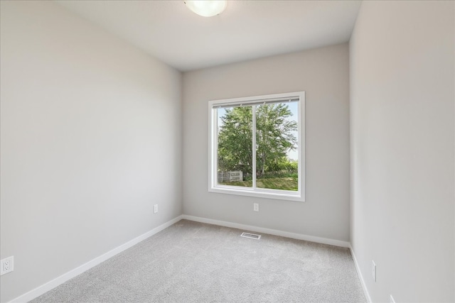 carpeted empty room featuring visible vents and baseboards