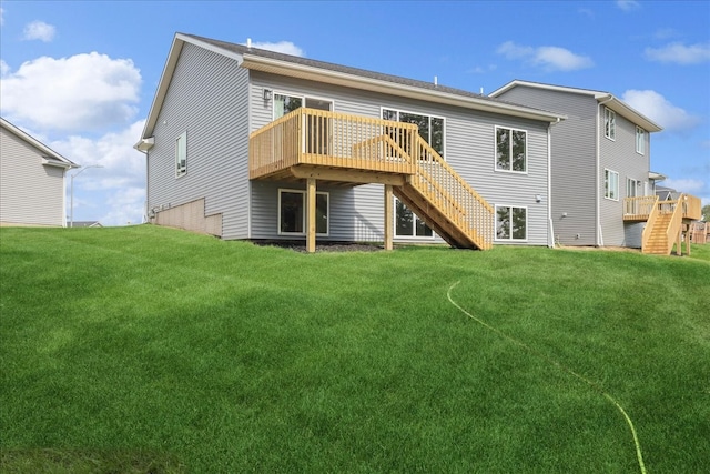 rear view of property with a lawn, a wooden deck, and stairs