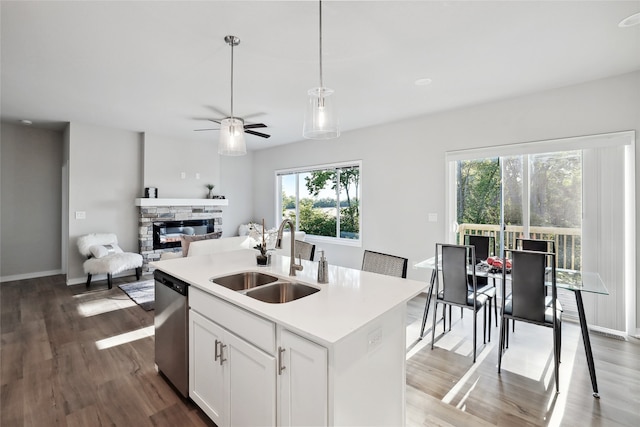 kitchen with dishwasher, an island with sink, light countertops, white cabinetry, and a sink