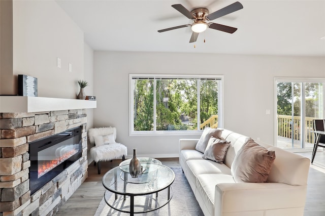 living room with light wood finished floors, a wealth of natural light, and a stone fireplace