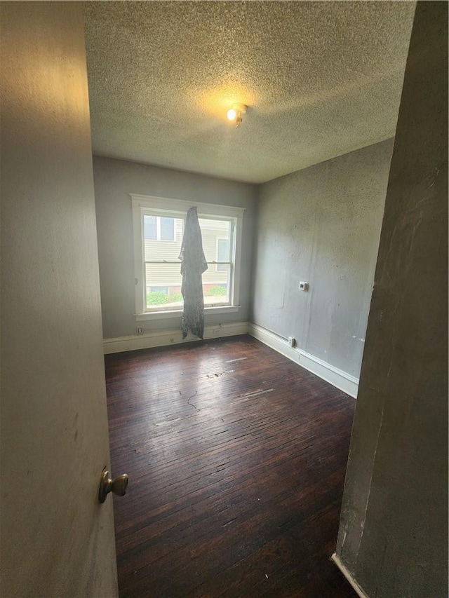 unfurnished room featuring a textured ceiling and dark wood-type flooring