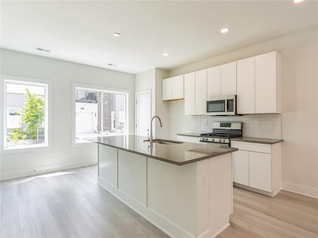 kitchen with stainless steel appliances, sink, a center island with sink, and white cabinets