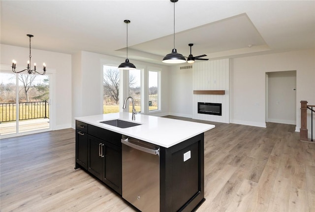 kitchen featuring sink, pendant lighting, dishwasher, a raised ceiling, and an island with sink