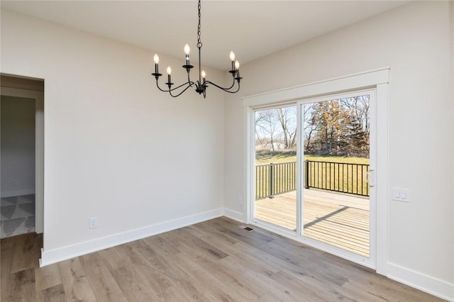 unfurnished dining area featuring a notable chandelier and light hardwood / wood-style flooring