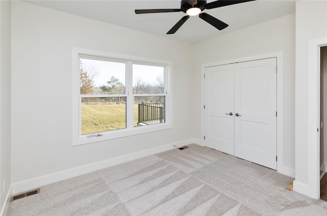 unfurnished bedroom with light carpet, ceiling fan, and a closet