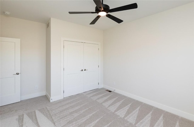 unfurnished bedroom featuring ceiling fan, light carpet, and a closet