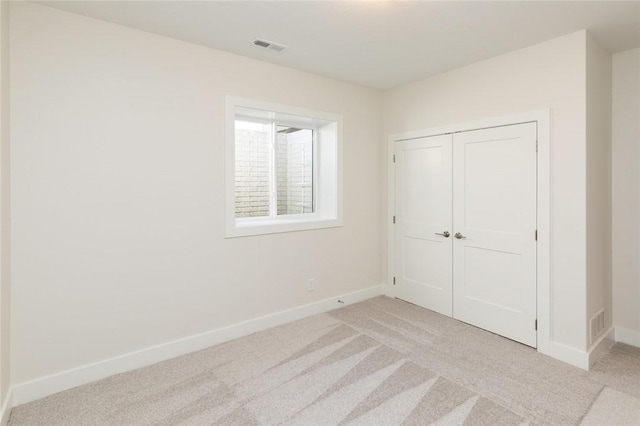 unfurnished bedroom with light carpet and a closet