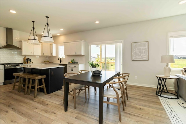 dining room featuring recessed lighting, a healthy amount of sunlight, baseboards, and light wood-style floors