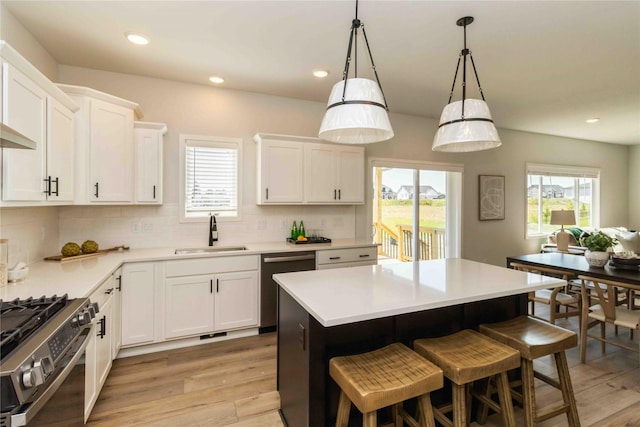 kitchen featuring light wood-style flooring, a sink, backsplash, white cabinetry, and appliances with stainless steel finishes