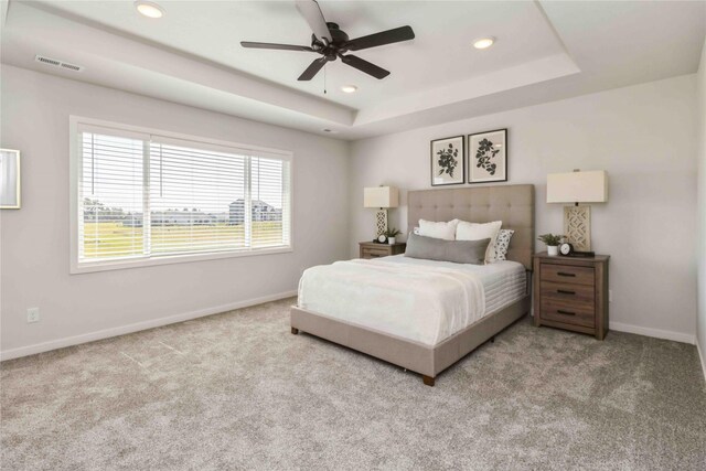 carpeted bedroom with baseboards, visible vents, a tray ceiling, recessed lighting, and ceiling fan