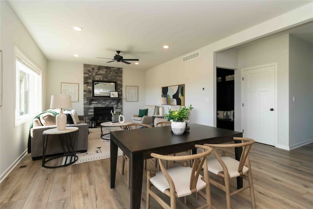 dining area featuring a fireplace, a ceiling fan, visible vents, and light wood-type flooring