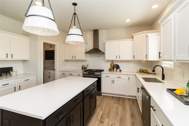 kitchen featuring wall chimney exhaust hood, sink, white cabinetry, a kitchen island, and stainless steel appliances