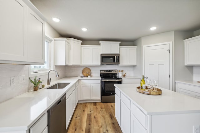 kitchen with white cabinetry, appliances with stainless steel finishes, sink, and light hardwood / wood-style flooring