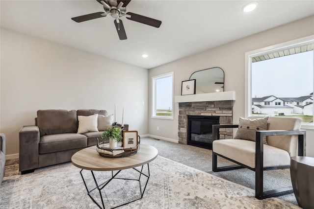 living room with ceiling fan, light colored carpet, and a fireplace