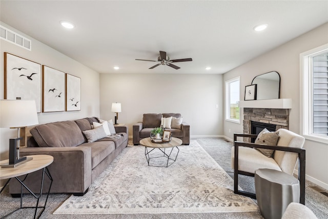 carpeted living room featuring a fireplace and ceiling fan