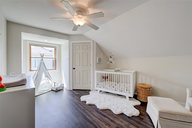 bedroom with vaulted ceiling, dark hardwood / wood-style floors, ceiling fan, and a nursery area