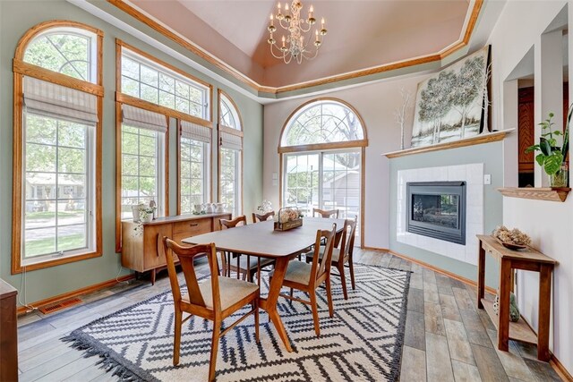 dining room with light hardwood / wood-style flooring, an inviting chandelier, a tile fireplace, and a wealth of natural light