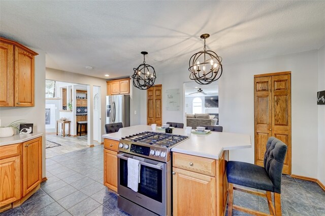 kitchen featuring hanging light fixtures, a textured ceiling, appliances with stainless steel finishes, a center island, and ceiling fan with notable chandelier