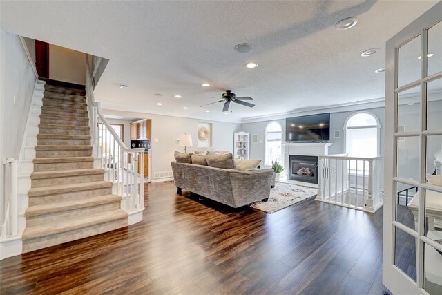 living room with a textured ceiling, ornamental molding, ceiling fan, and hardwood / wood-style flooring