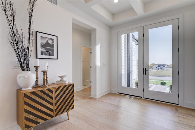 doorway to outside featuring coffered ceiling, light wood-type flooring, and beam ceiling