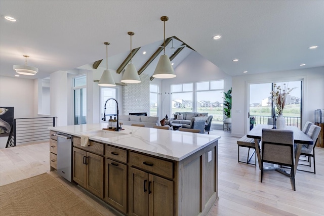 kitchen with an island with sink, decorative light fixtures, sink, and light hardwood / wood-style floors