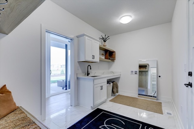 kitchen featuring a textured ceiling, sink, and white cabinets