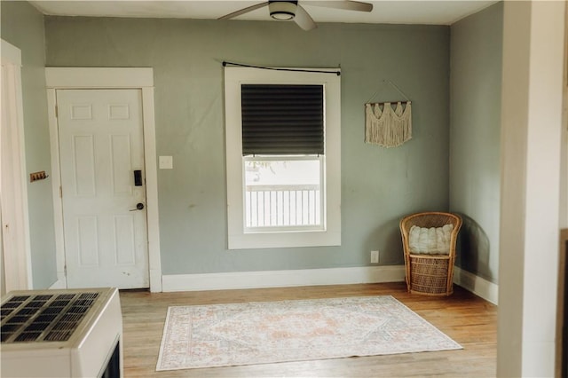 foyer featuring wood finished floors, ceiling fan, baseboards, and heating unit
