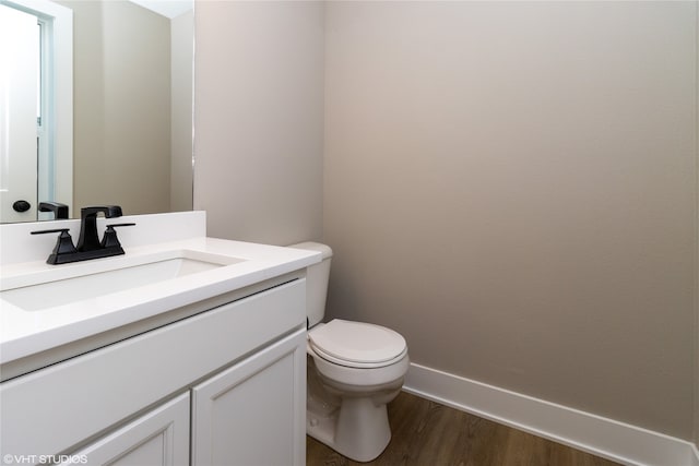 bathroom with toilet, vanity, and wood-type flooring