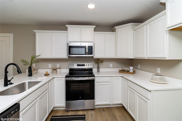 kitchen with white cabinetry, stainless steel appliances, sink, and light hardwood / wood-style flooring