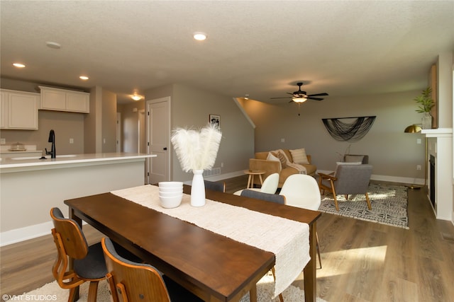 dining space with a textured ceiling, hardwood / wood-style flooring, ceiling fan, and sink