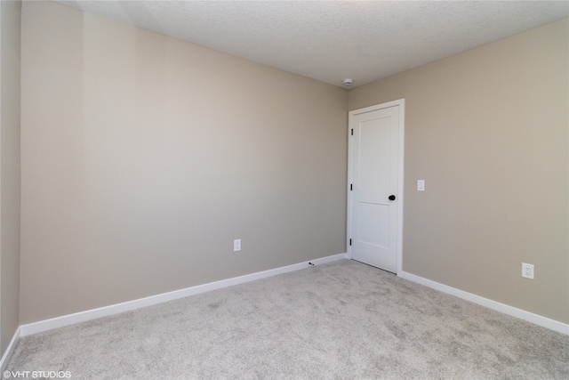 unfurnished room with light colored carpet and a textured ceiling