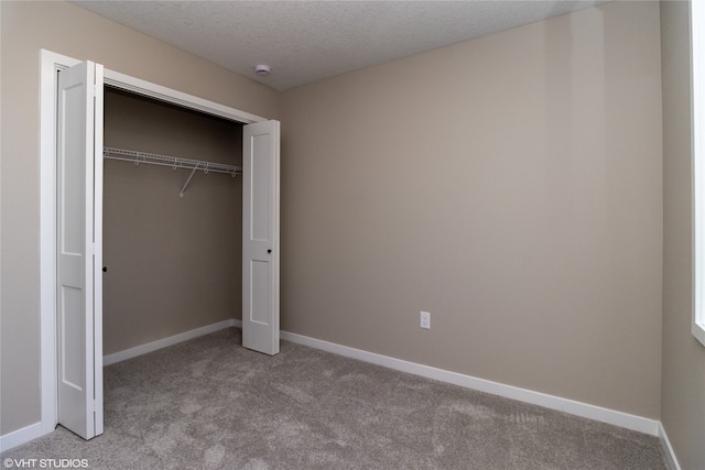 unfurnished bedroom with a textured ceiling, light carpet, and a closet