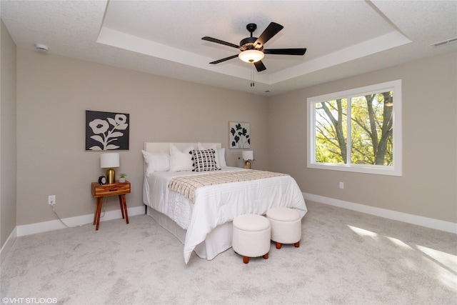 bedroom featuring a tray ceiling, carpet, and ceiling fan